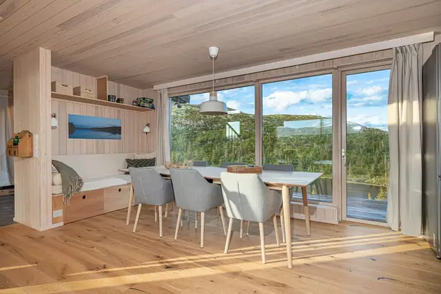 Spisestuen har nydelgi utsikt til et lokal vann og plass til langbord, samt utgang til terrassen. Plassbygget sittebenk med dype skuffer for praktisk oppbevaring følger hytta.