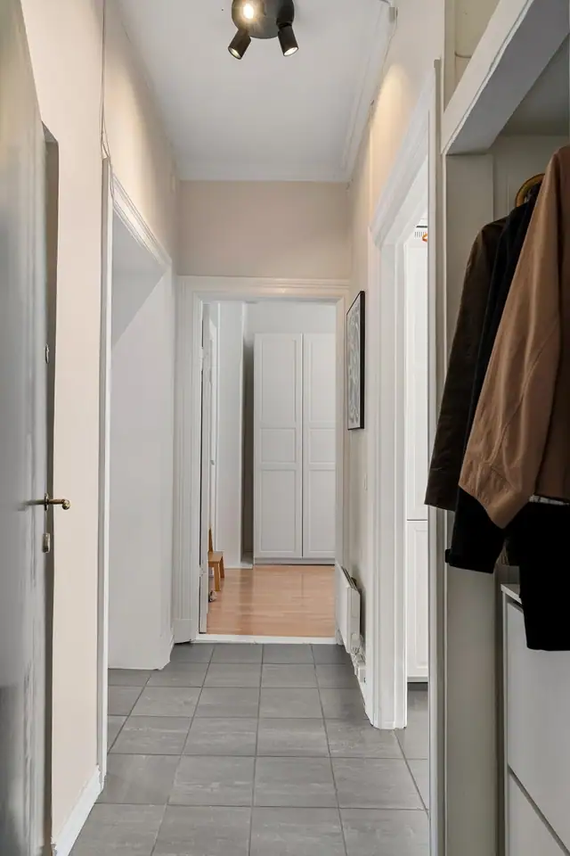 Innbydende flislagt entré/gang deler opp leilighetens øvrige rom.