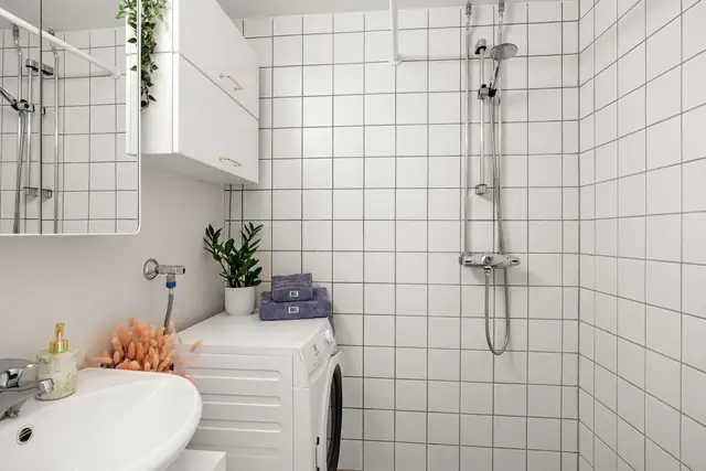 Badet er utstyrt med servant, wc og åpen dusj med dusjforheng.